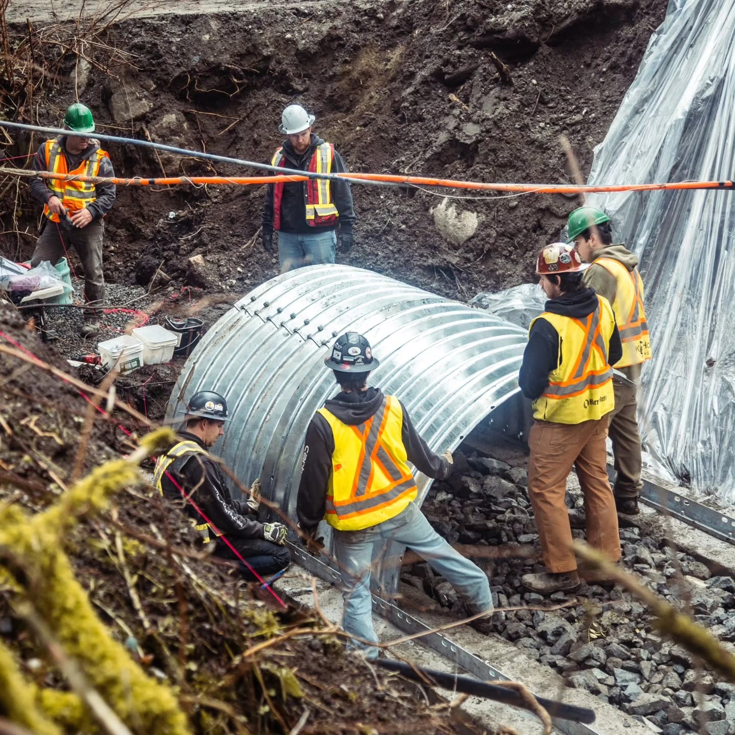 Radius Excavation team installing a corrugated steel culvert on a slope repair